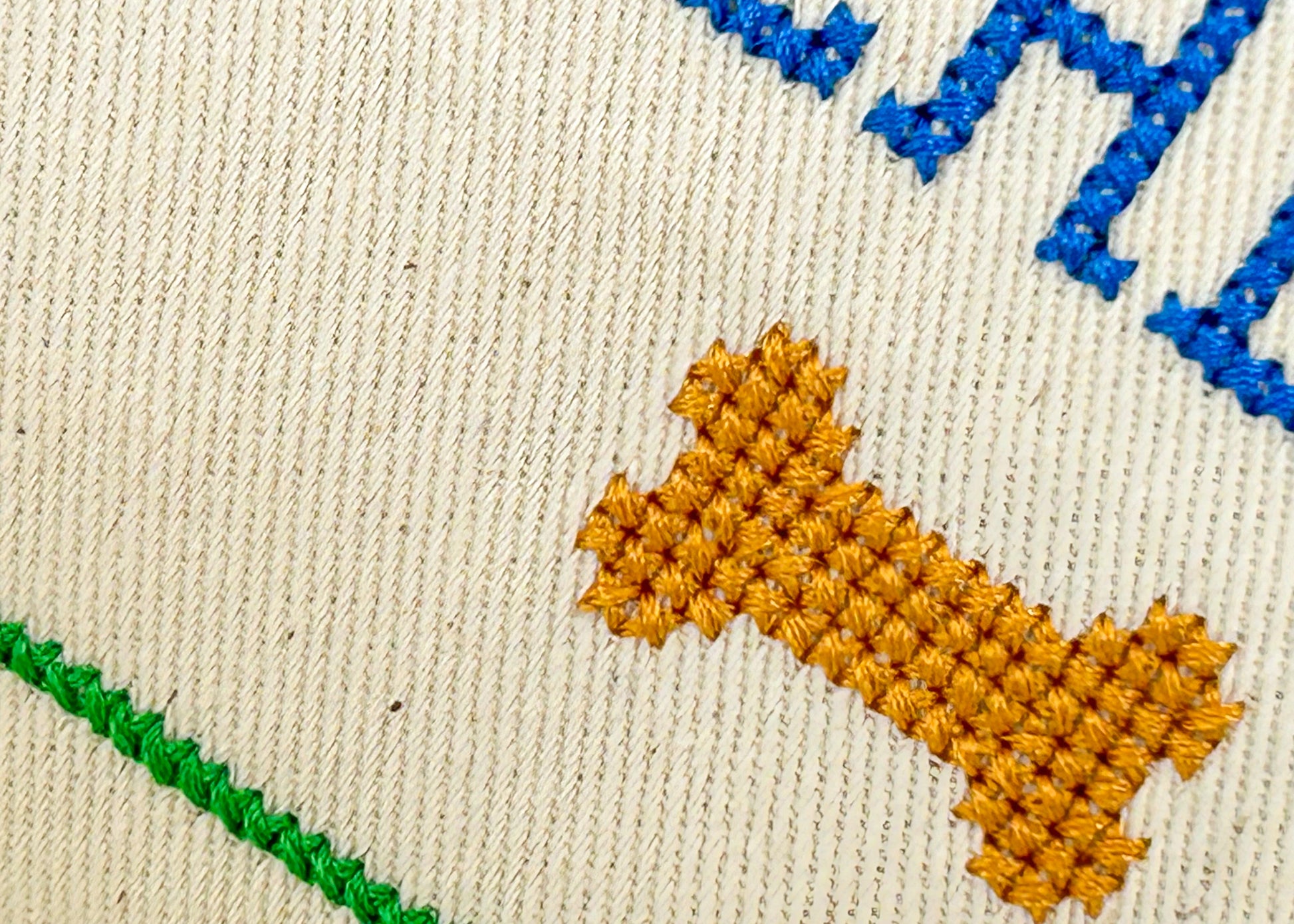 Embroidered design on fabric with a yellow dog, blue text, and green line.