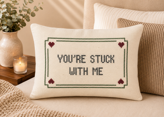 Decorative pillow with 'You're Stuck with Me' text on a bed.