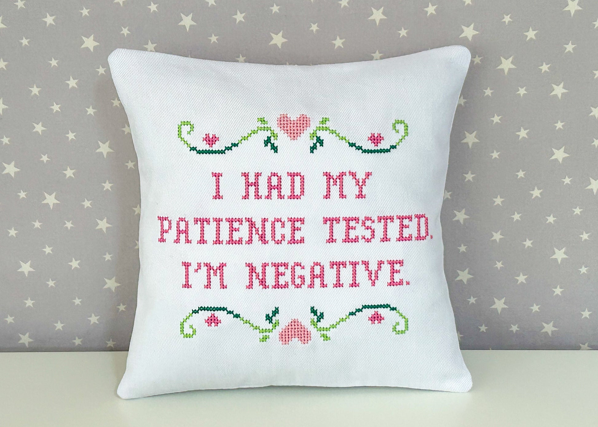 Decorative pillow with cross-stitched text on a star-patterned background