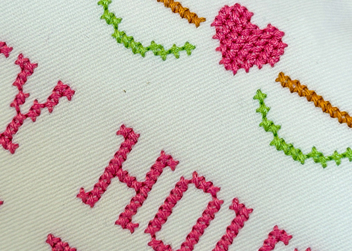 Embroidered text and decorative elements on a white fabric background