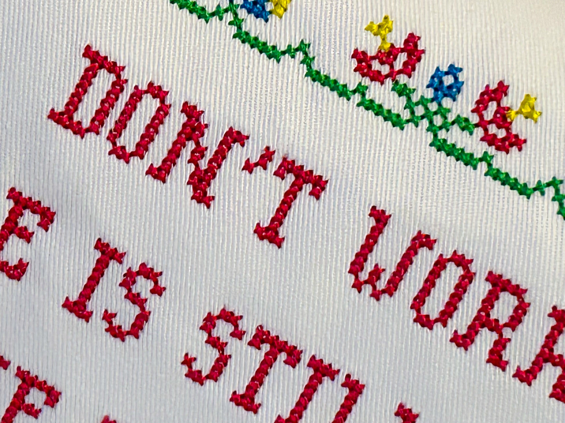 Cross stitch embroidery text in red with red and blue flowers