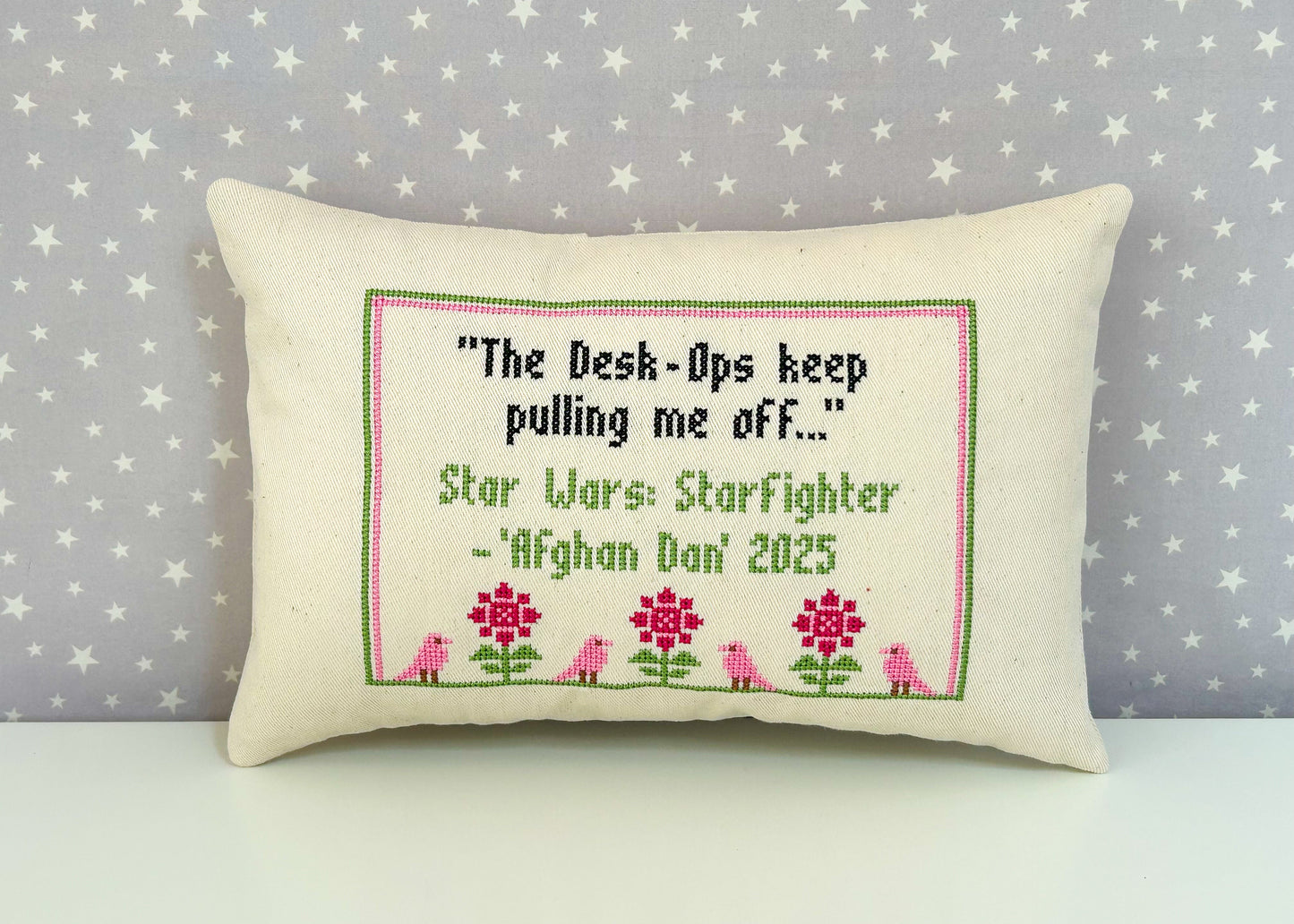 Decorative pillow with embroidered text and floral design on a star-patterned background