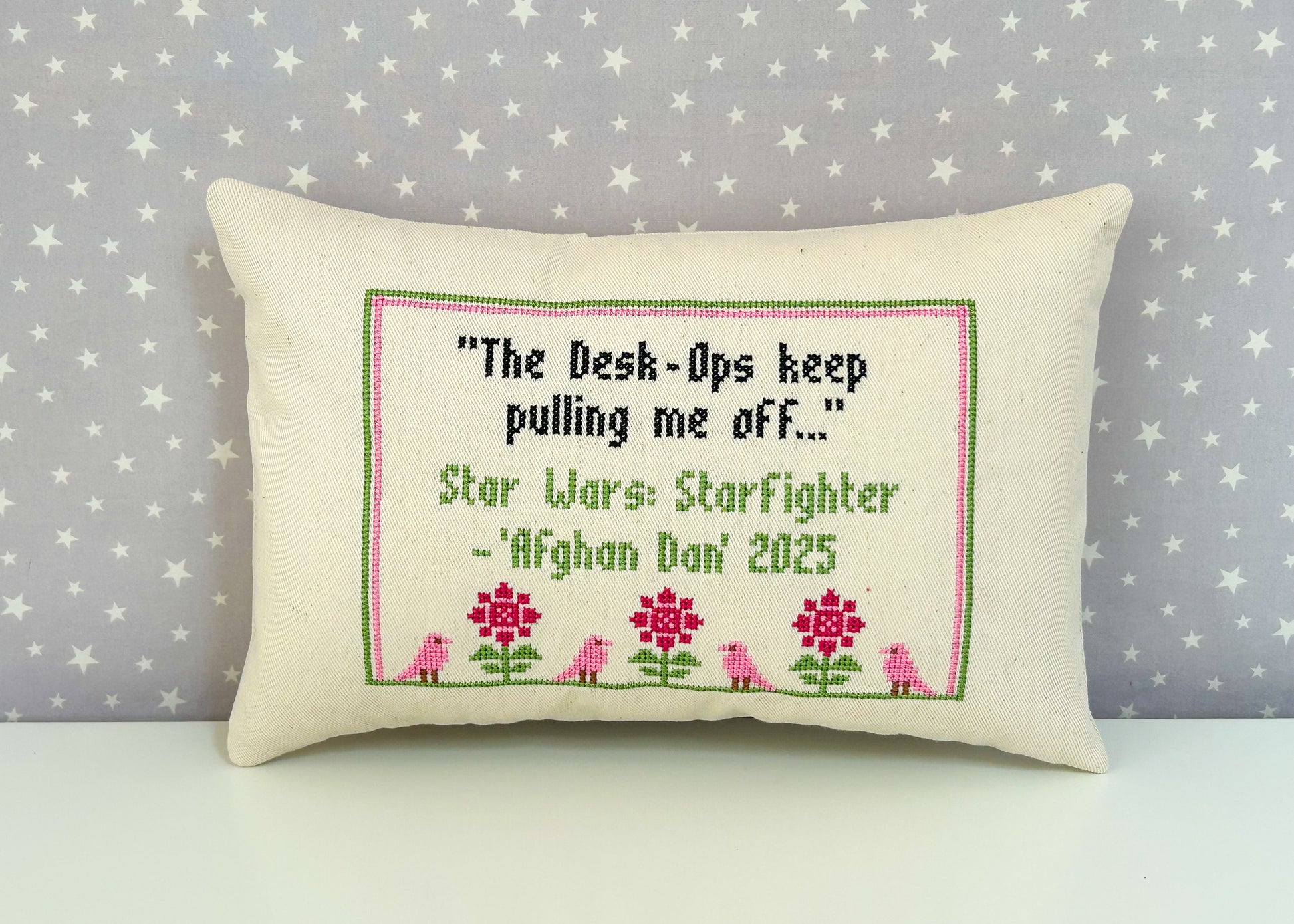 Decorative pillow with embroidered text and floral design on a star-patterned background