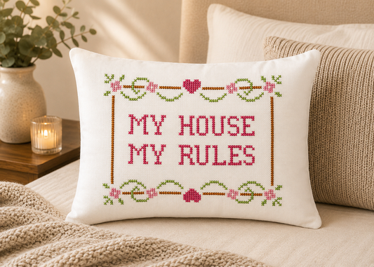 Decorative pillow with cross-stitched text 'My House My Rules' on a bed.