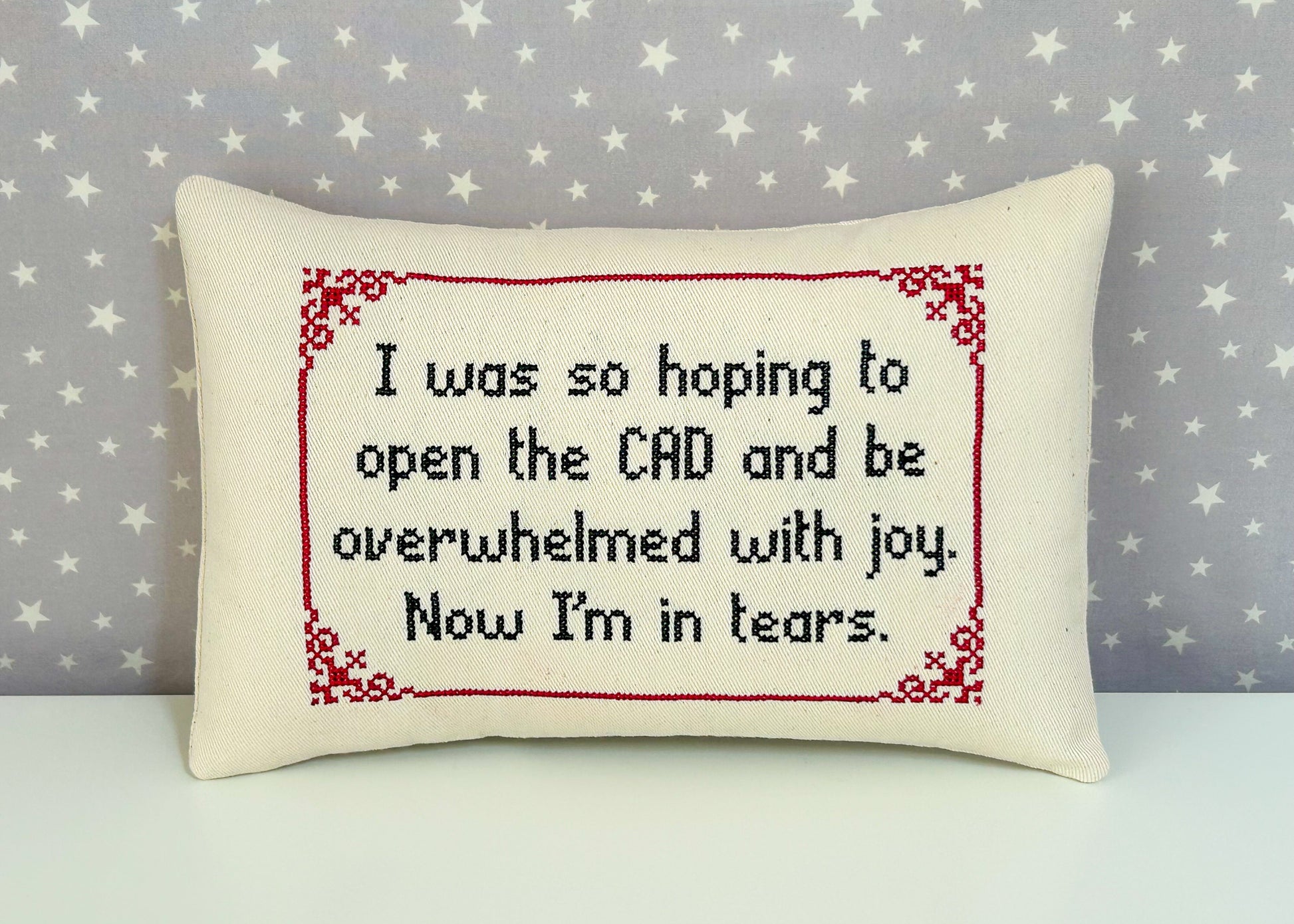 Decorative pillow with cross-stitched text on a star-patterned background