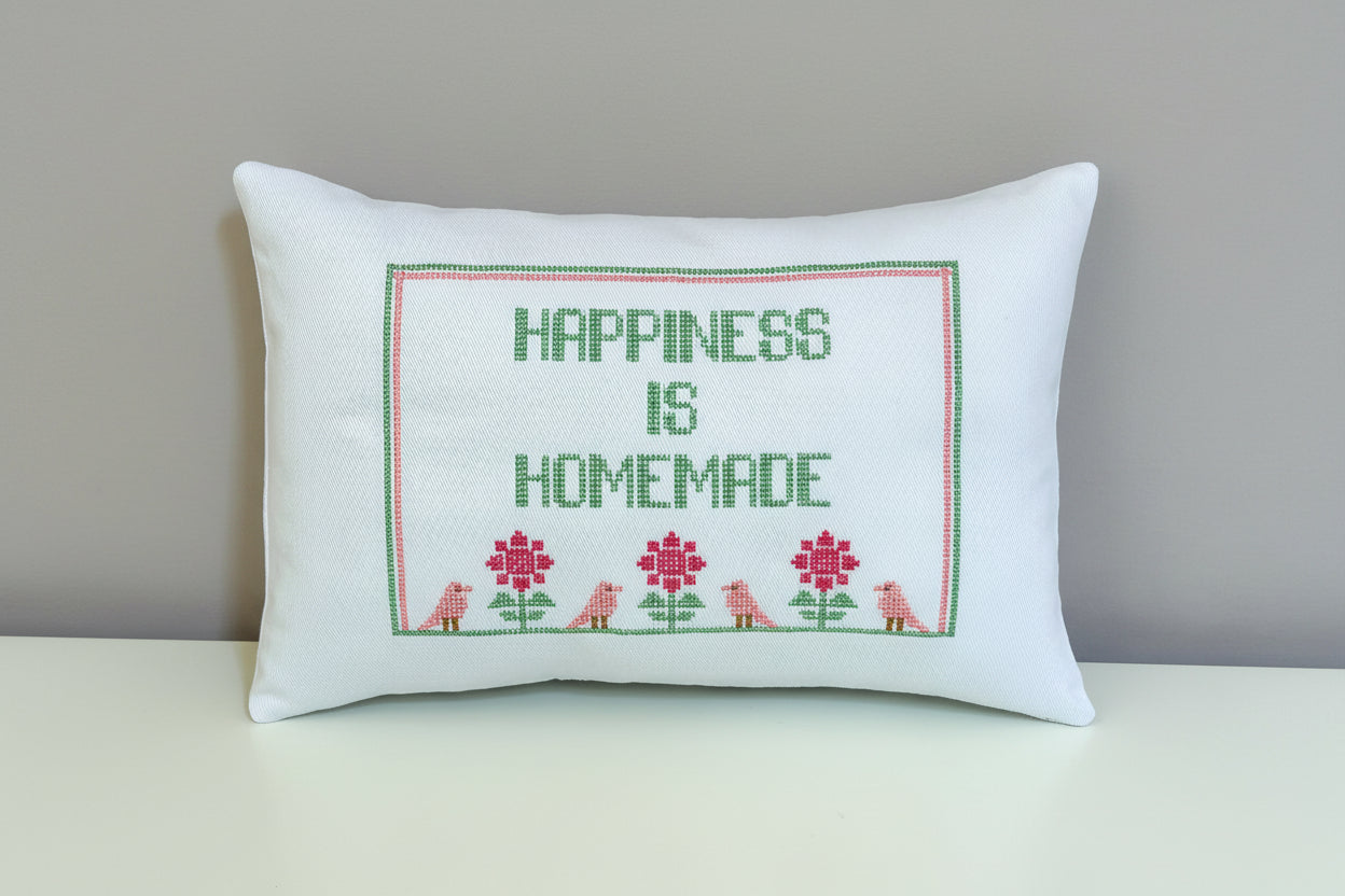 Decorative pillow with 'Happiness is Homemade' text on a grey background