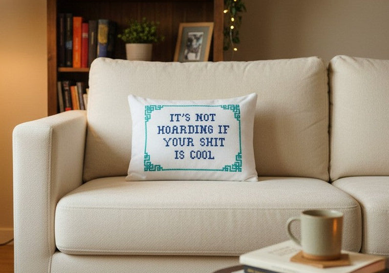 Beige sofa with a decorative pillow featuring text, books, and a mug on a table in the background.
